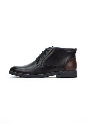 Bottines en cuir noir avec un accent en cuir marron, bout rond, fermeture à lacets à six œillets et semelle en caoutchouc plate.