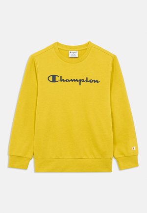 Žlutá mikina s dlouhým rukávem a kulatým výstřihem s černým logem "Champion" přes hrudník a malým logem na manžetě levého rukávu.