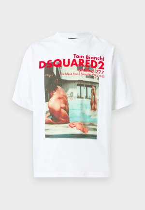 White cotton T-shirt featuring a large photographic print of two individuals by a pool and red graphic text overlay with brand details.