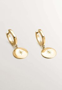 Pendientes de aro de oro con un acabado suave, que cuentan con un charm circular colgante grabado con un diseño de estrella. Silueta simple y pulida.
