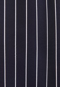 Tissu foncé avec des fines rayures verticales blanches uniformément espacées créant un motif rayé classique.
