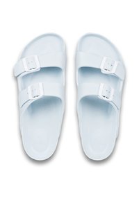 Ljusbl�å sandaler med två justerbara vita spännen, slätt material, öppen tå-design, platt sula, minimalistisk stil och utan mönster.