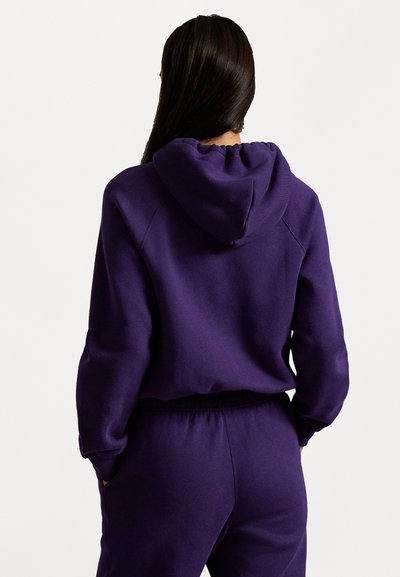 Purple cropped hoodie with a drawstring hood, soft texture, ribbed cuffs, and matching waistband. Displayed from the back.