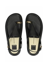 Černé tanga sandály s texturovanou podrážkou, které mají zlaté kovové detaily a nastavitelné pásky kolem kotníku. Hladký materiál s minimálním designem.