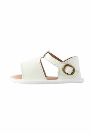 Witte leren babysandaal met open teen, enkelriem en messing gesp op witte achtergrond.