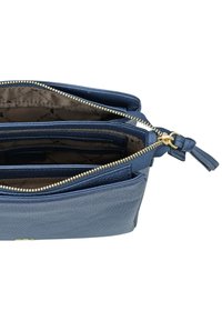 Borsa in pelle blu con superficie testurizzata, multiple tasche e una cerniera dorata con una linguetta decorativa. L'interno è foderato in marrone.