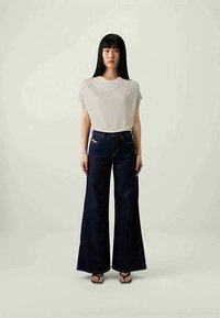 Light grey short-sleeve top paired with dark blue wide-leg denim jeans. The fabric appears soft, with a smooth texture and minimal detailing.