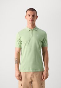 Hellgrünes Poloshirt mit kurzen Ärmeln und Kragen, das ein kleines Logo auf der Brust und einen weichen, strukturierten Stoff aufweist.