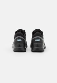 Scarpe sportive nere con tomaia in rete, collare imbottito e suola in gomma testurizzata. Presentano un discreto dettaglio del logo sul tallone.