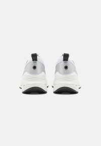 Vista posteriore di scarpe da ginnastica con una combinazione di colori bianco e grigio. Le caratteristiche includono una tomaia testurizzata, una linguetta e una suola nera a contrasto.