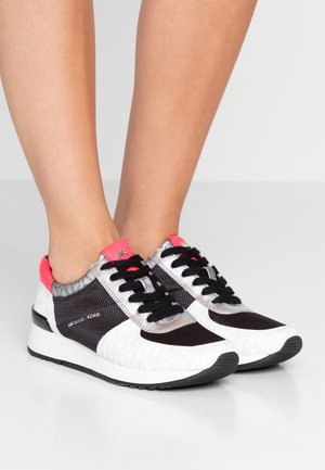Baskets noir et blanc avec des textures en maille et lisses. Présentent des accents argentés, un col rose, des lacets noirs et un panneau latéral à motifs.