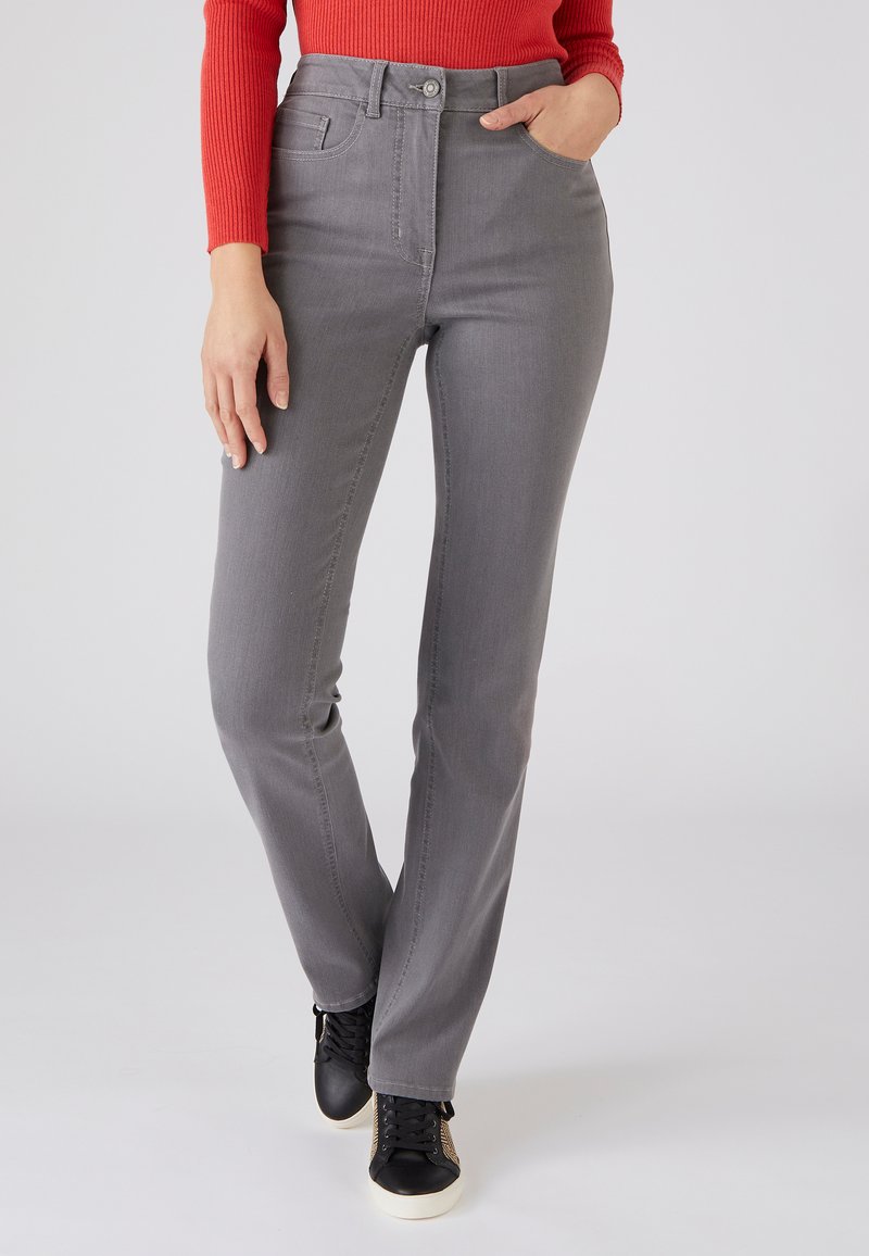 Jeans altos de talle gris con una textura suave, bolsillos frontales y cierre de botón, combinados con zapatillas negras con suelas blancas.