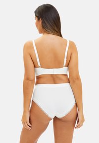 Ensemble de lingerie blanche comprenant un soutien-gorge en tissu doux et lisse avec des bretelles réglables, associé à un slip taille haute orné de détails en dentelle.