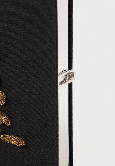 Caderno de tecido preto com um clip prateado e um design texturizado de contas douradas a acentuar a capa. Costura visível e detalhes nas bordas presentes.