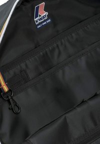 Interno in nylon nero di una borsa Kway con due tasche orizzontali con cerniera, un'etichetta in alto e una tracolla multicolore con ferramenta.
