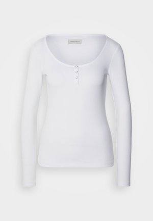 Top bianco a maniche lunghe con scollatura a barchetta, texture a coste e tre bottoni argentati decorativi sul davanti.