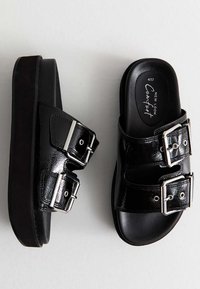 Sandali platform neri in pelle sintetica lucida, con due fibbie argentate regolabili e design slip-on che presenta una soletta sagomata.