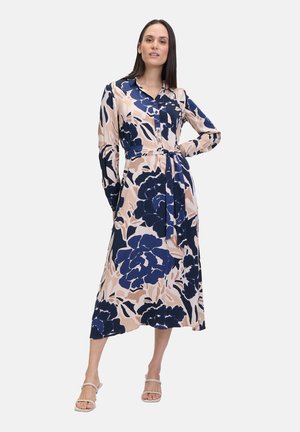 Langärmliges Hemdblusenkleid mit Blumenmuster, das große marineblaue Blumen auf einem hellen Pfirsichhintergrund zeigt. Es enthält einen passenden Gürtel.