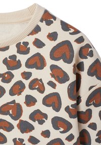 Cremfarbener Pullover mit einem Muster aus braunen und dunkelgrauen, herzförmigen und abstrakten Flecken, mit einem gerippten Halsausschnitt.