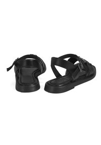 Black leather sandals with a flat sole, featuring crisscross straps and a buckle detail. Smooth texture and minimalist design.