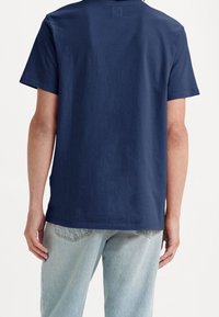 Mørkeblå bomulds-t-shirt med korte ærmer, lige afslutning og et enkelt design, parret med lyseblå denim jeans.