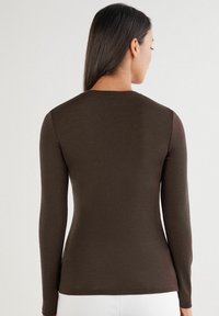 Brauner langärmeliger Oberteil aus einem weichen, dehnbaren Material. Es hat einen runden Ausschnitt und eine körpernahe Silhouette, ohne zusätzliche Muster oder Akzente.