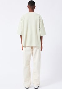 Light green oversized T-shirt with elbow-length sleeves, paired with off-white wide-leg pants. Soft texture and simple design.