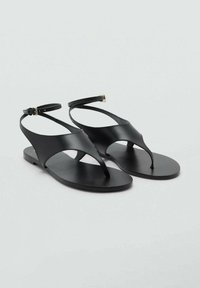 Sandale plate negre din piele netedă. Prezintă un design minimalist cu o curea pentru degete, decupaje laterale și o curea ajustabilă la gleznă.