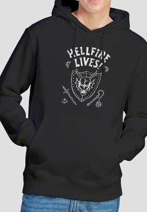 Person wearing a black hoodie with white "Hellfire Lives!" text, a horned skull shield, sword, flail, and geometric shapes design on front.