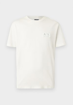 T-shirt branca de algodão com decote redondo e mangas curtas, apresentando um pequeno retângulo com um logótipo na parte superior esquerda.