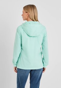 Light blue windbreaker jacket with a hood, elastic cuffs, and a casual fit. Smooth texture, simple design, and no visible patterns or accents.