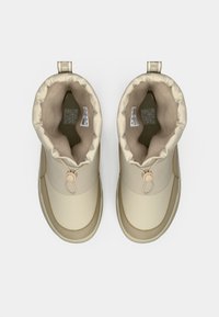 Beige waterdichte boots met een zachte, gewatteerde kraag, trekkoordsluiting en contrasterende bruine stiksels. Gecoate binnenvoering.
