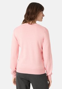 Jasnoróżowy sweter z długimi rękawami, okrągłym dekoltem, prążkowanym dołem i mankietami, o gładkiej, miękkiej fakturze i prostym wzornictwie.