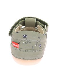 Sanda le de cuero verde con forma redondeada, tira de Velcro y patrón de lunares; presenta un logotipo rojo de Kickers en el talón.