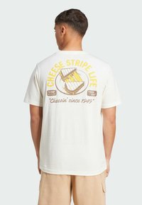 White cotton t-shirt featuring a graphic design on the back with text "CHEESE STRIPE LIFE" and an illustration of cheese. Short sleeves.
