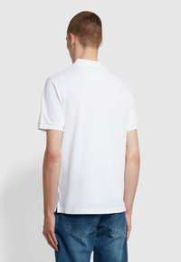 Witte polo met korte mouwen, gemaakt van een zachte stof en met een geribde kraag, voorzien van zijventilatieopeningen en een schoon, minimalistisch ontwerp.