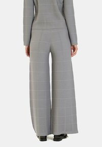 Pantalones de pierna ancha grises que presentan una tela texturizada con un patrón de cuadrícula, ofreciendo un ajuste holgado y acentuados por dobladillos a la altura del tobillo.