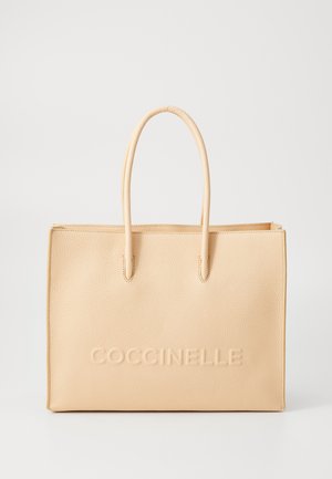 Sac cabas en cuir beige avec une texture lisse, doté de deux poignées et d'un logo "Coccinelle" en relief sur l'avant. Forme rectangulaire.