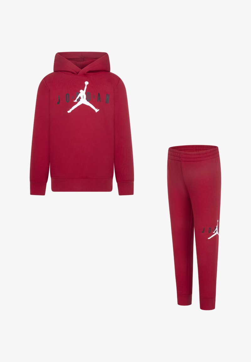 Sudadera roja con capucha y pantalones de chándal a juego, hechos de una tela suave. La sudadera cuenta con un bolsillo tipo canguro y un logo Jumpman blanco; los pantalones tienen una cinturilla elástica.