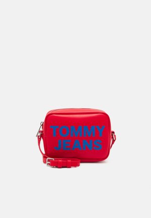Rode rechthoekige crossbodytas met verstelbare riem, zilveren ritssluiting en "TOMMY JEANS" in grote blauwe letters op de voorkant.
