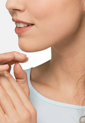 Nahaufnahme eines Frauengesichts, das glatte Haut, dezentes Make-up, weiche Lippen und ein blaues Oberteil mit einem runden Halsausschnitt zeigt. Die Hände berühren sanft das Kinn.