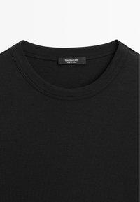 Sort t-shirt med rund hals og syning ved kraven samt en etiket med teksten "Massimo Dutti Made in China" inde i halsåbningen.