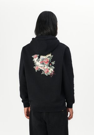 Felpa nera con cappuccio, caratterizzata da una grafica dettagliata di un teschio con rose e il testo "Santa Cruz" sul retro. Materiale in cotone.