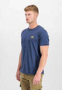 Dunkelblaues Baumwoll-T-Shirt mit Rundhalsausschnitt, kurzen Ärmeln und einem gelben Logo auf der Brust. Glatte Textur mit lockerer Passform.