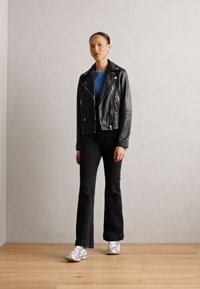Black leather biker jacket, blue shirt, black skinny jeans, and silver sneakers. Simple design with zippers and a fitted silhouette.