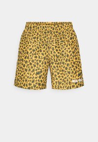Calções com padrão de leopardo com um fundo amarelo e manchas pretas, apresentando uma cintura elástica e um logo branco no canto inferior direito.