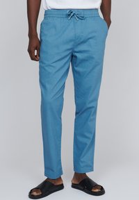 Pantaloni ușori de culoare albastru deschis, cu talie elastică și șnur. Completați cu buzunare laterale și o croială conică, asortați cu sandale negre.