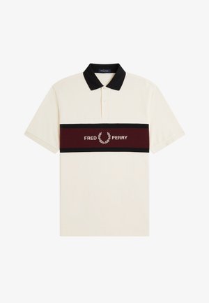 Short-sleeve beige polo shirt with black collar and horizontal maroon stripe featuring "Fred Perry" text and laurel logo across the chest.