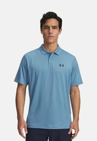 Svetlomodrá polo košeľa vyrobená z priedušného materiálu, s golierom a krátkymi rukávmi, s čiernym logom Under Armour na ľavej hrudi.