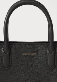 Borsa a mano nera in pelle con superficie texturizzata, dotata di due manici robusti e un logo dorato. Design minimalista con sottili dettagli di cucitura.